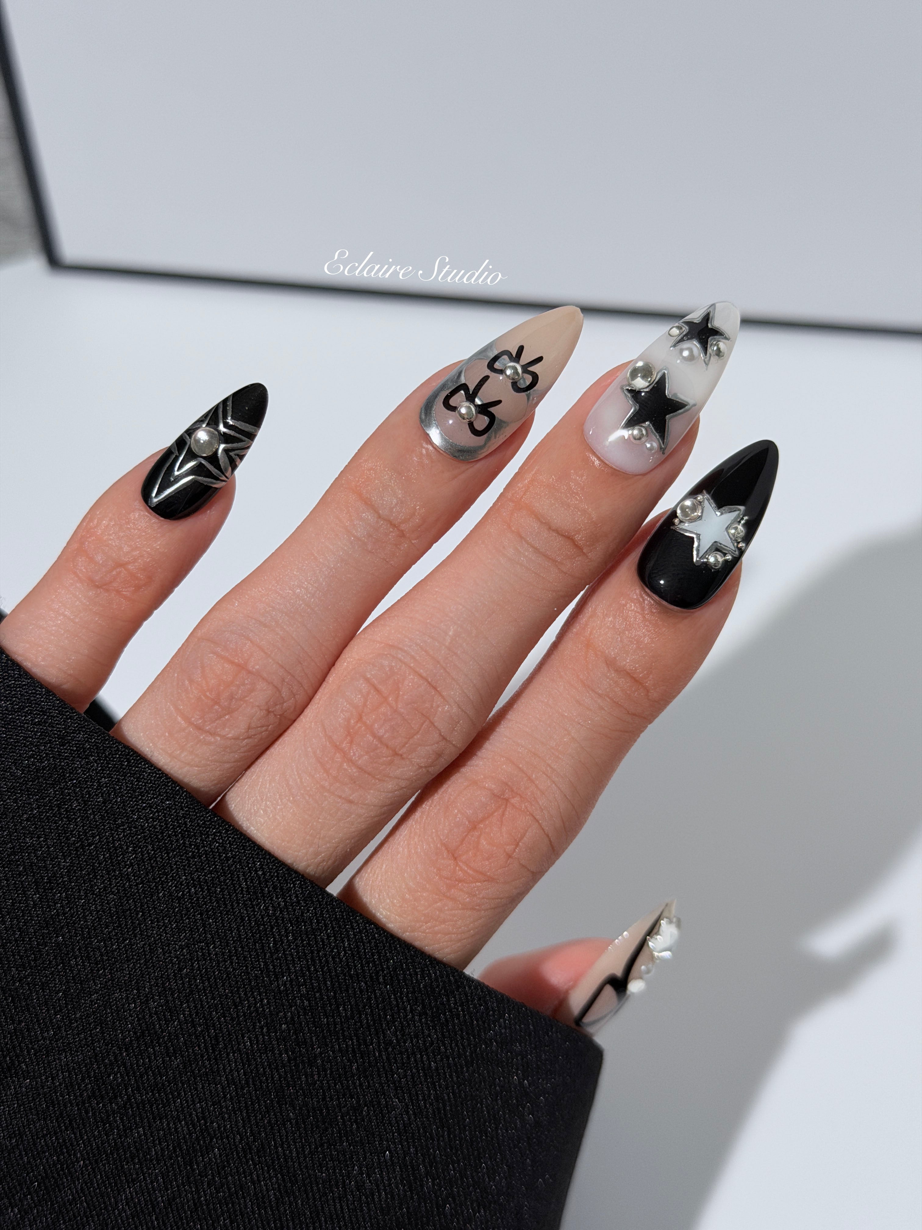 Handmade black, white, and nude press-on nails featuring bows, star charms, and pearl embellishments.