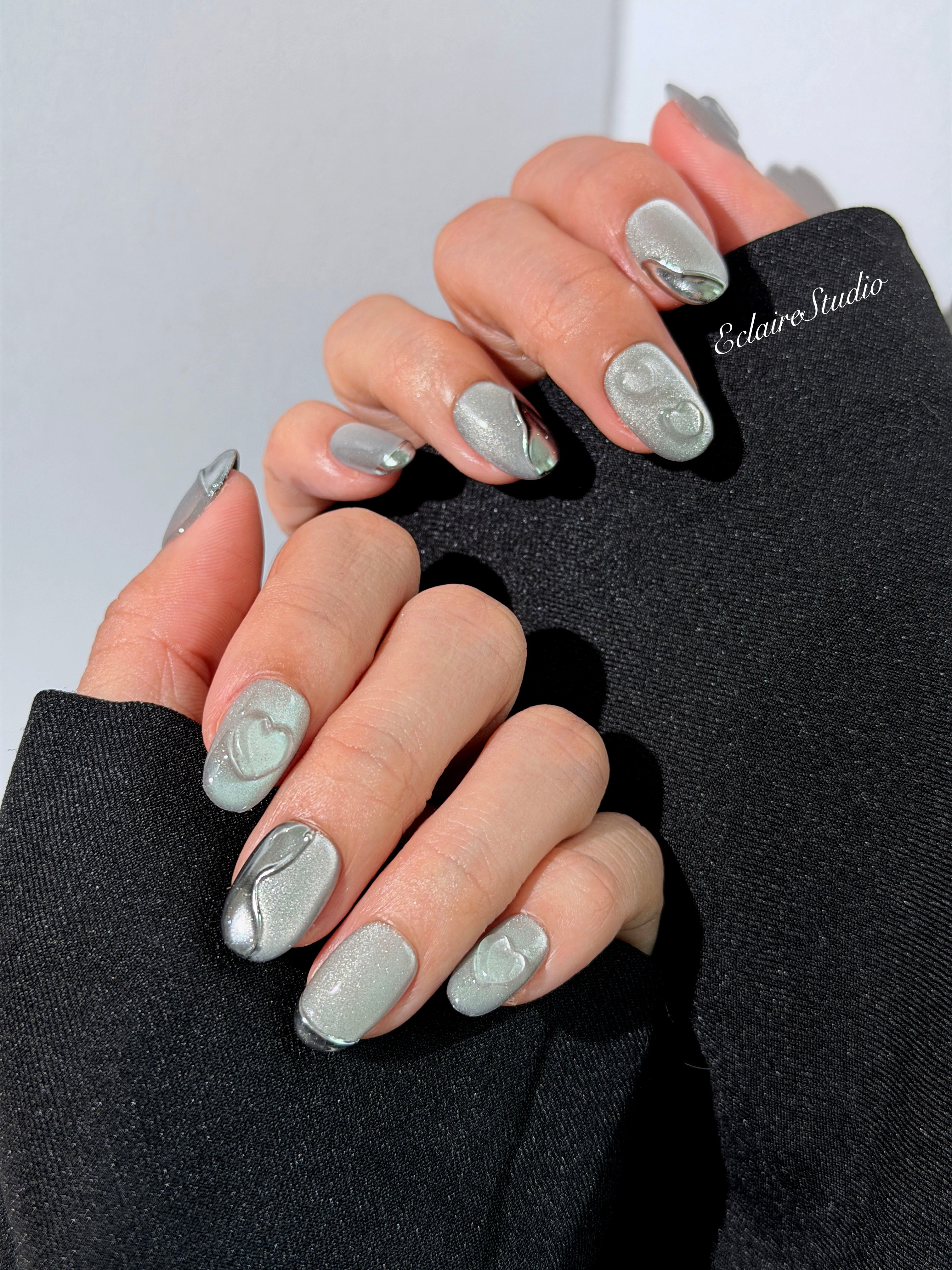 Extra short silver cat-eye press-on nails with chrome ripple accents and 3D heart details, minimalist winter aesthetic.

