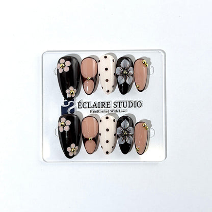 Cocoa Cameo almond press-on nails with espresso and blush bases, brown polka dots on ivory, sculpted flowers, pink daisies, and gold beads.