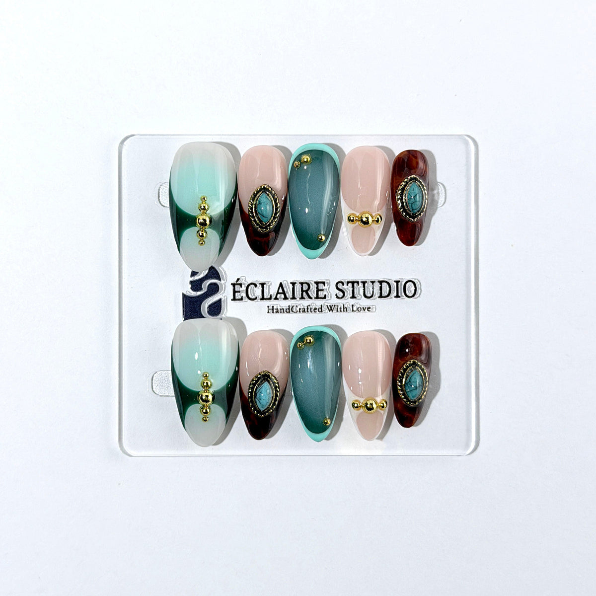 Jasmine’s Secret almond press-on nails with teal and blush bases, tortoiseshell French tips, turquoise-toned oval jewels, gold frames, and gold beads.