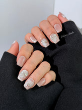 Short coffin pink nude cat-eye press-on nails with lace texture and pearl bow accents in a soft romantic winter style.

