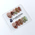 Olive Reverie short almond press-on nails with brown and green cat-eye shimmer, olive French tips, animal prints, floral art, and raised gold details.