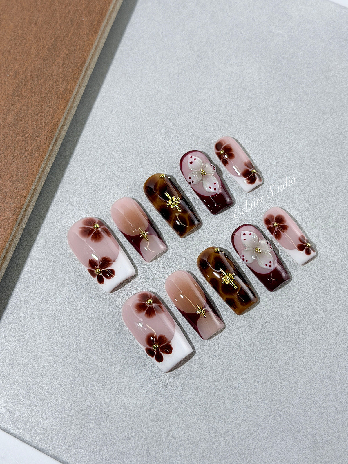 Amber Bloom square press-on nails with blush pink bases, French tips, brown hand-painted flowers, tortoiseshell accents, ivory 3D flowers, and gold details.