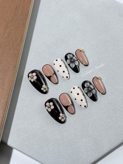 Cocoa Cameo almond press-on nails with espresso and blush bases, brown polka dots on ivory, sculpted flowers, pink daisies, and gold beads.