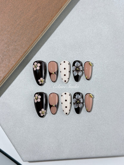 Cocoa Cameo almond press-on nails with espresso and blush bases, brown polka dots on ivory, sculpted flowers, pink daisies, and gold beads.
