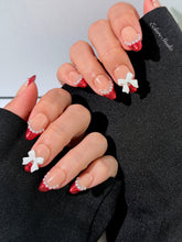 Red Ribbon press-on nails with glazed red chrome French tips, pearl trim, and 3D white bow accents.”