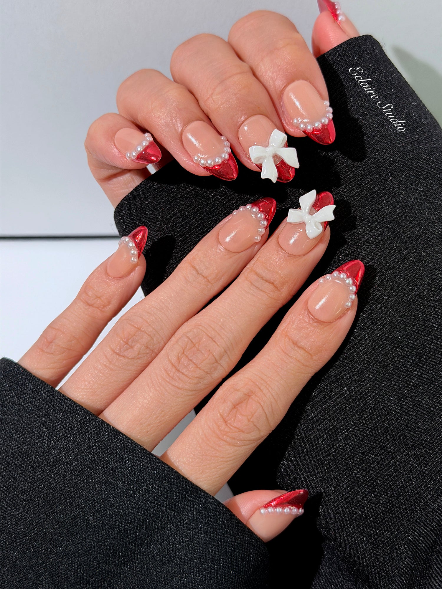 Red Ribbon press-on nails with glazed red chrome French tips, pearl trim, and 3D white bow accents.”