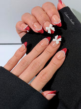 Red Ribbon press-on nails with glazed red chrome French tips, pearl trim, and 3D white bow accents.”