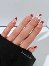 Red Ribbon press-on nails with glazed red chrome French tips, pearl trim, and 3D white bow accents.”