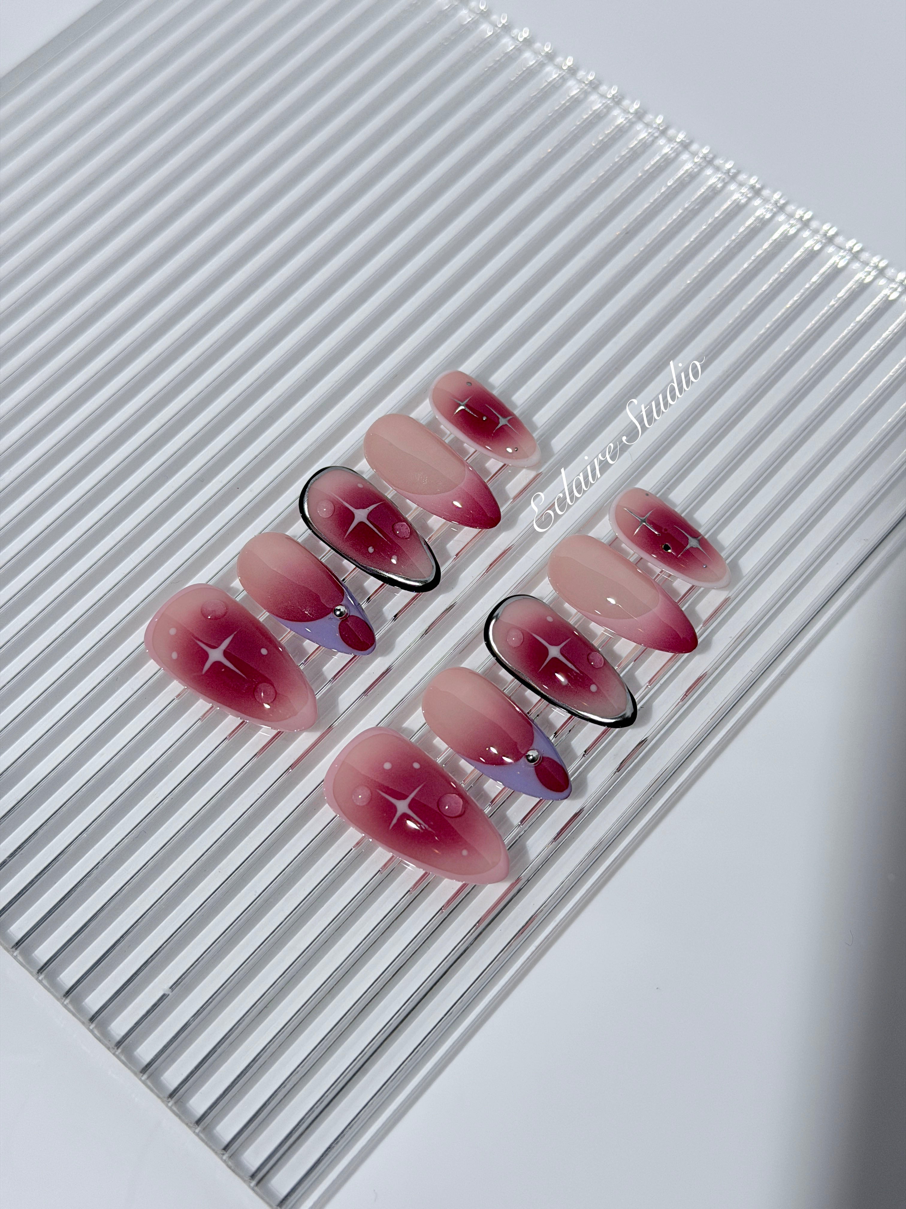 Plum and blush ombré nails with star accents and abstract black outlines — Sugar Plum Fairy–inspired.