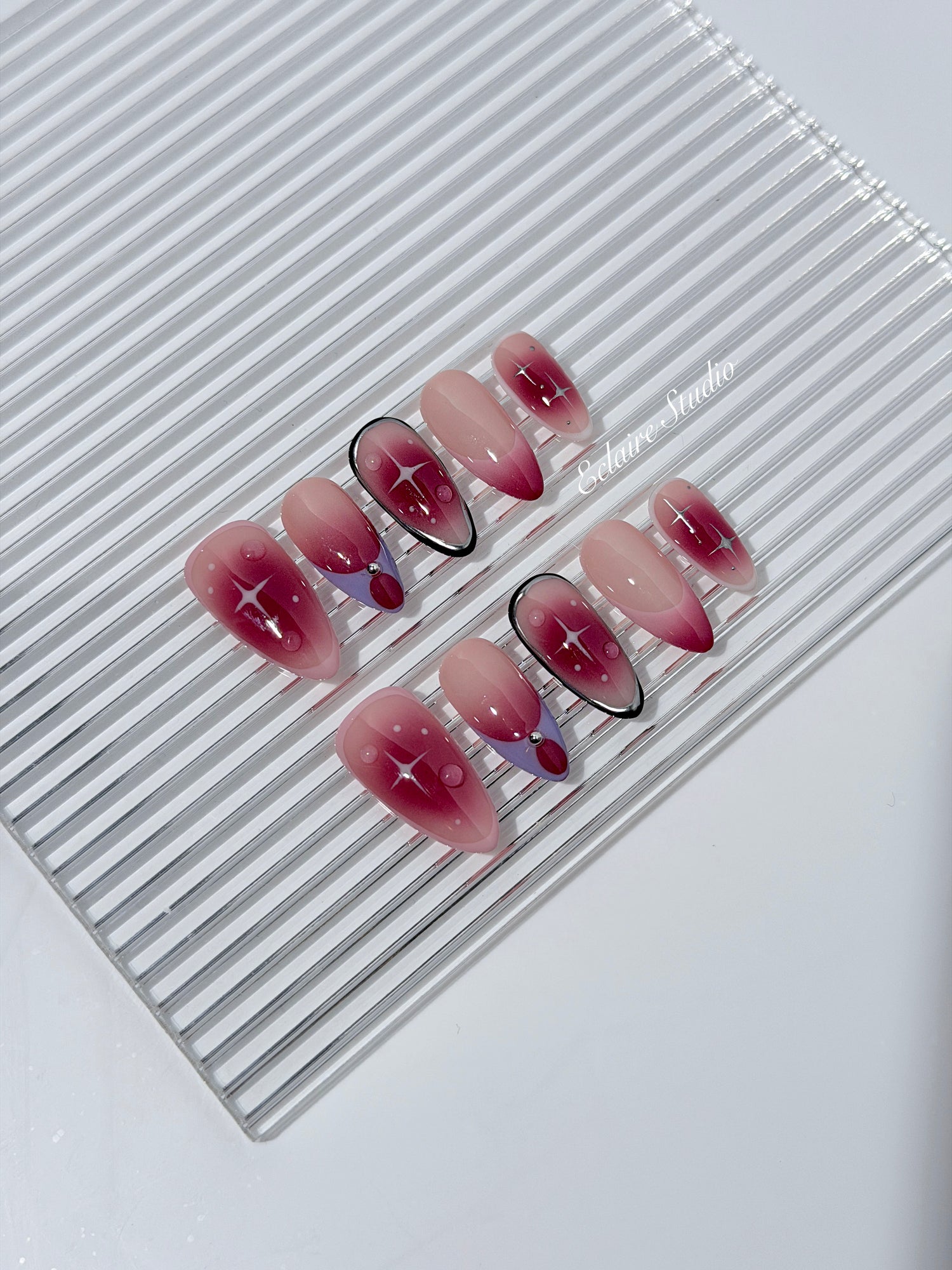Plum and blush ombré nails with star accents and abstract black outlines — Sugar Plum Fairy–inspired.