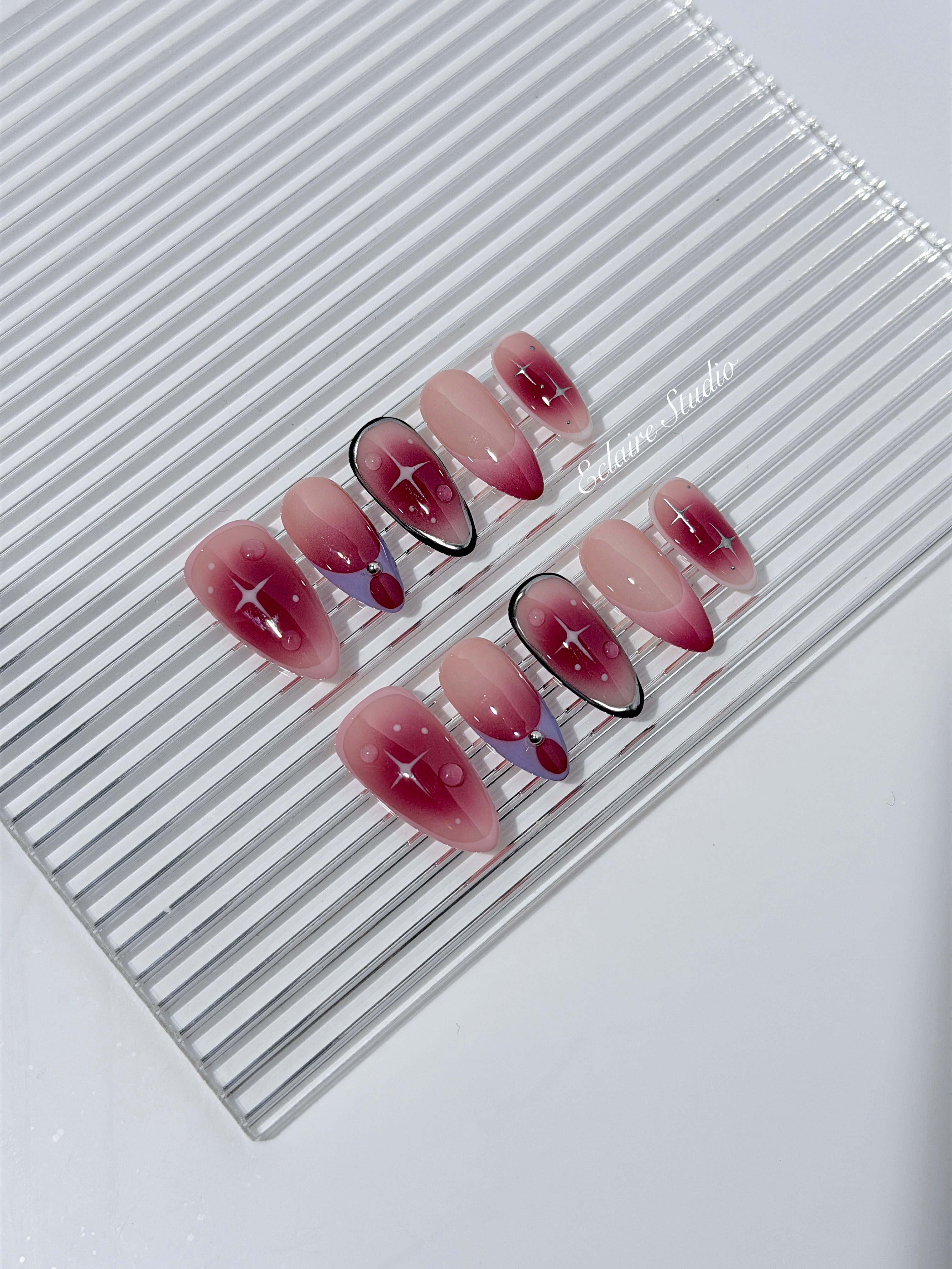 Plum and blush ombré nails with star accents and abstract black outlines — Sugar Plum Fairy–inspired.