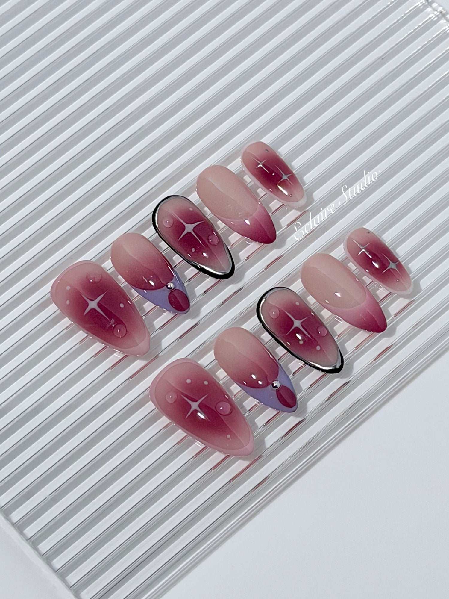 Plum and blush ombré nails with star accents and abstract black outlines — Sugar Plum Fairy–inspired.