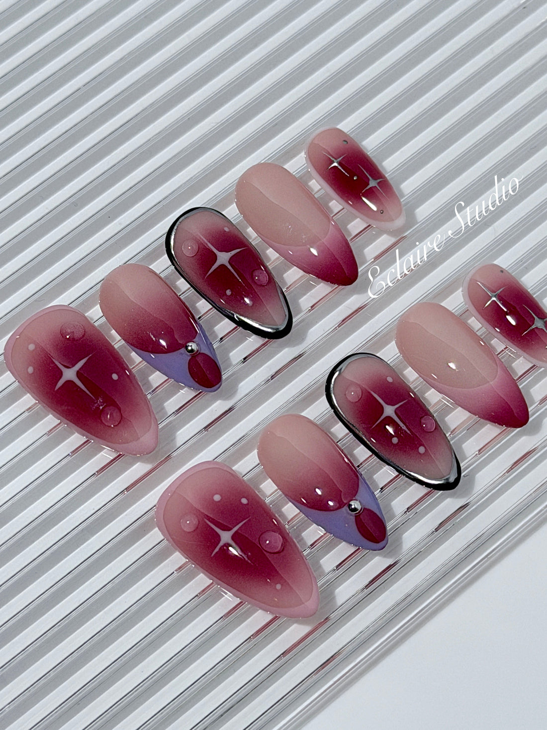 Plum and blush ombré nails with star accents and abstract black outlines — Sugar Plum Fairy–inspired.