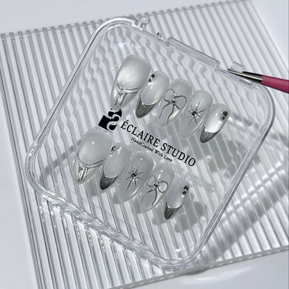Silver cat-eye press-on nails featuring glazed chrome French tips and fine-line bow and starburst designs.