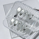 Silver cat-eye press-on nails featuring glazed chrome French tips and fine-line bow and starburst designs.