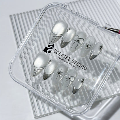 Silver cat-eye press-on nails featuring glazed chrome French tips and fine-line bow and starburst designs.