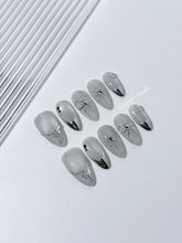 Silver cat-eye press-on nails featuring glazed chrome French tips and fine-line bow and starburst designs.