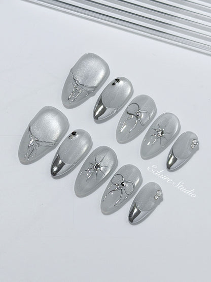 Silver cat-eye press-on nails featuring glazed chrome French tips and fine-line bow and starburst designs.