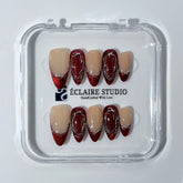 Red press-on nails with deep red cat-eye base, silver strokes, and nude contrast — Éclaire Nail Studio