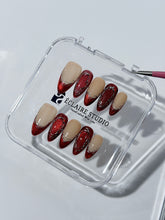 Red press-on nails with deep red cat-eye base, silver strokes, and nude contrast — Éclaire Nail Studio