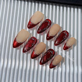 Red press-on nails with deep red cat-eye base, silver strokes, and nude contrast — Éclaire Nail Studio