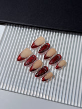 Red press-on nails with deep red cat-eye base, silver strokes, and nude contrast — Éclaire Nail Studio