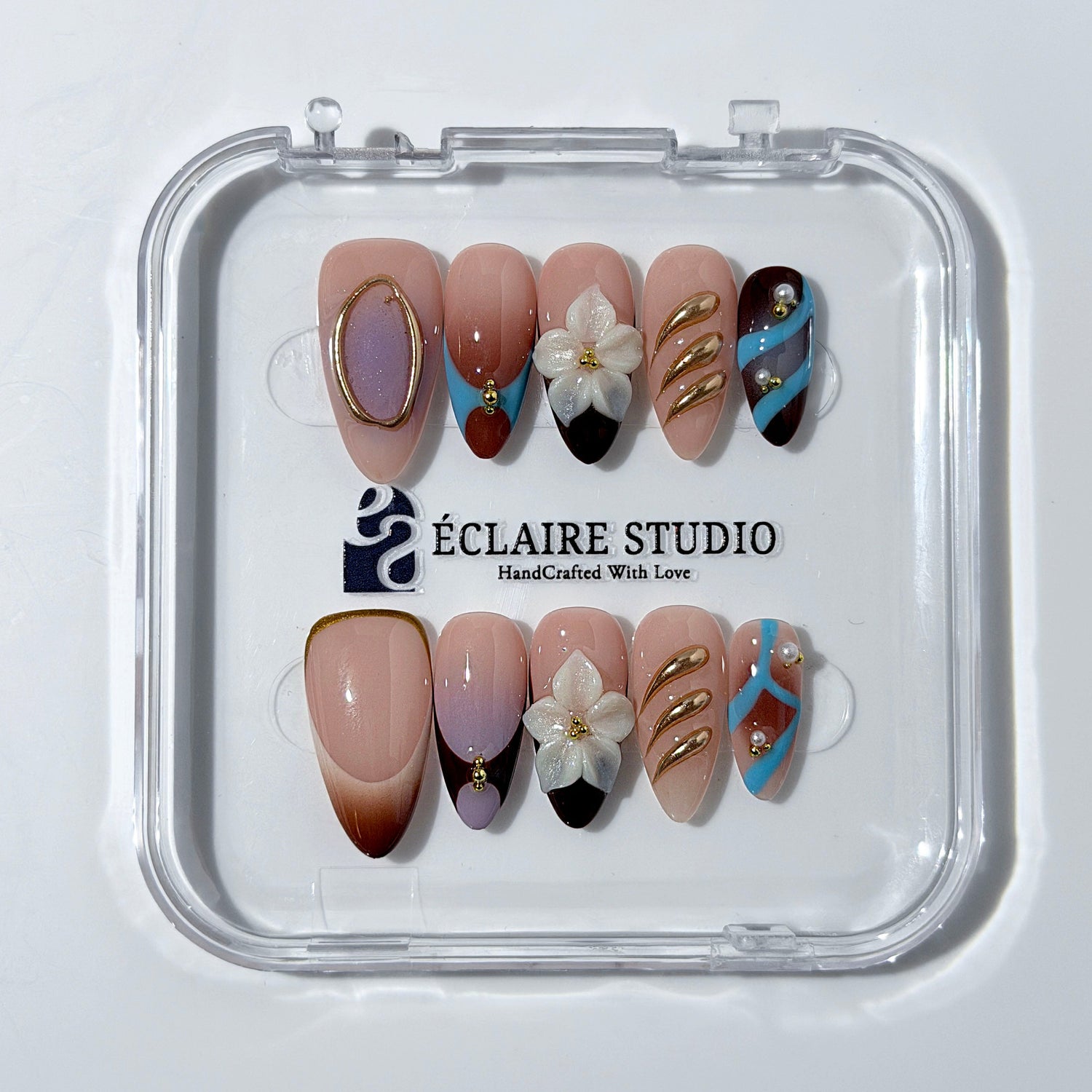 Warm gradient nails with gold trim, 3D white flowers, and blue accents inspired by the Nutcracker character