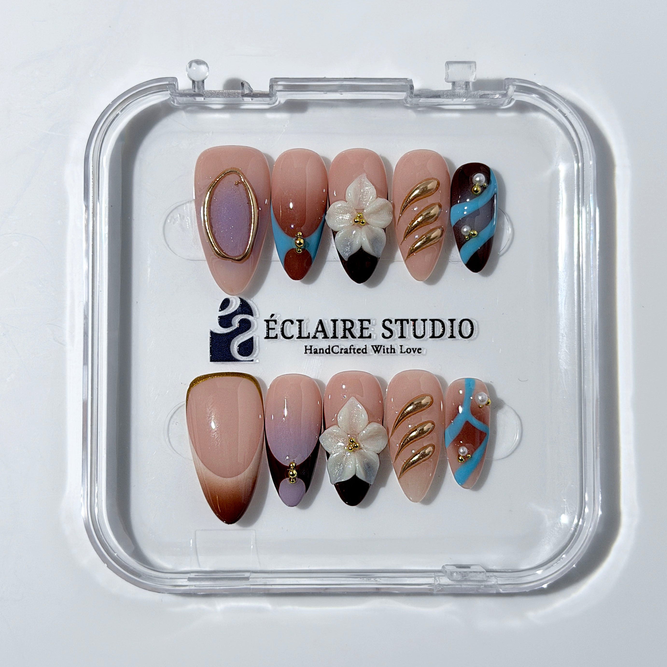 Warm gradient nails with gold trim, 3D white flowers, and blue accents inspired by the Nutcracker character