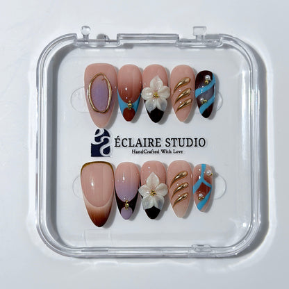 Warm gradient nails with gold trim, 3D white flowers, and blue accents inspired by the Nutcracker character