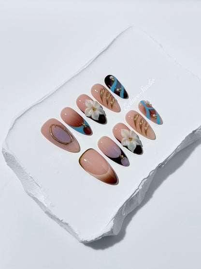 Warm gradient nails with gold trim, 3D white flowers, and blue accents inspired by the Nutcracker character