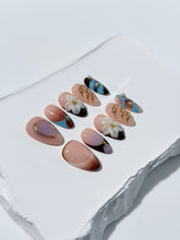 Warm gradient nails with gold trim, 3D white flowers, and blue accents inspired by the Nutcracker character