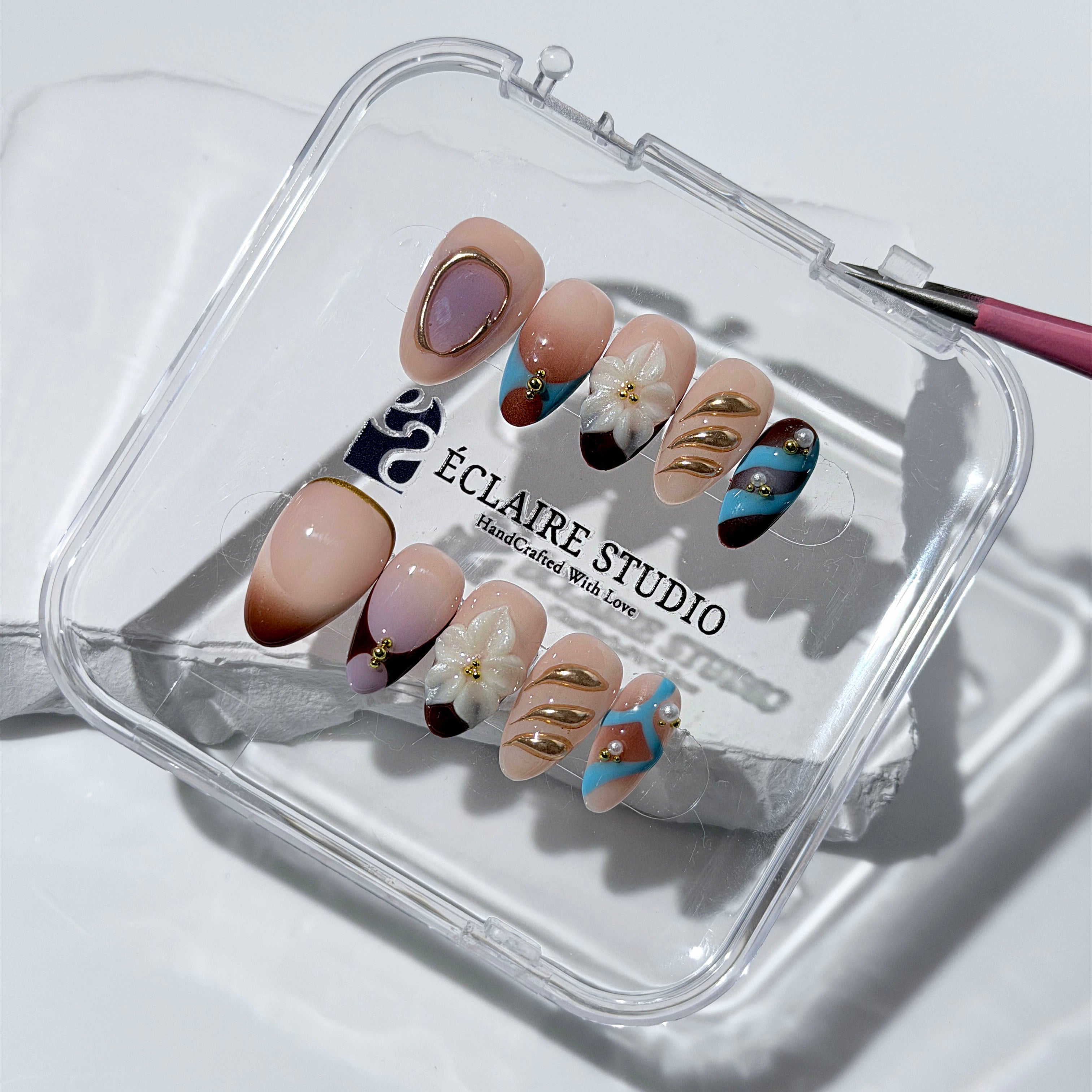 Warm gradient nails with gold trim, 3D white flowers, and blue accents inspired by the Nutcracker character