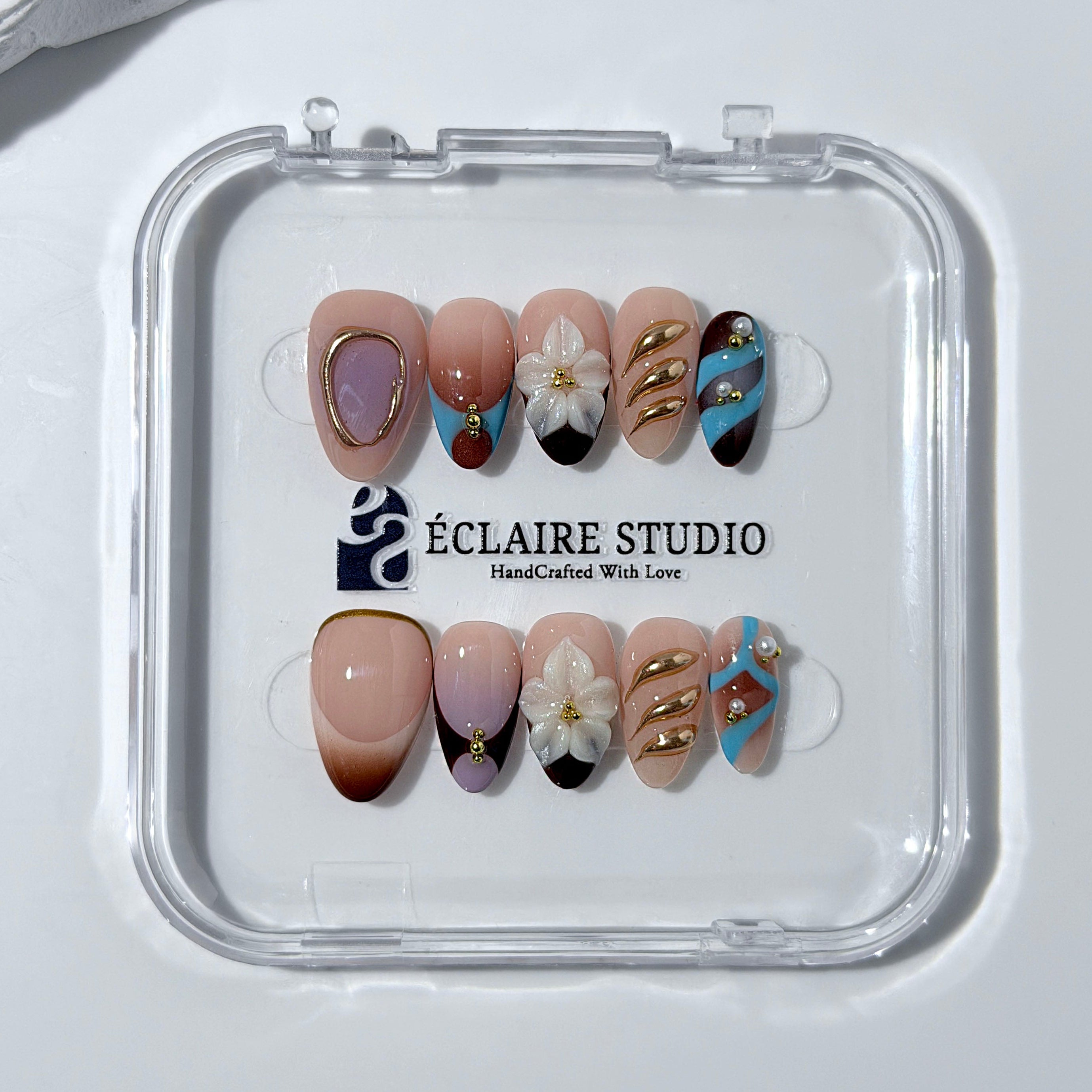 Warm gradient nails with gold trim, 3D white flowers, and blue accents inspired by the Nutcracker character