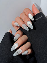 Silver cat-eye press-on nails featuring glazed chrome French tips and fine-line bow and starburst designs.
