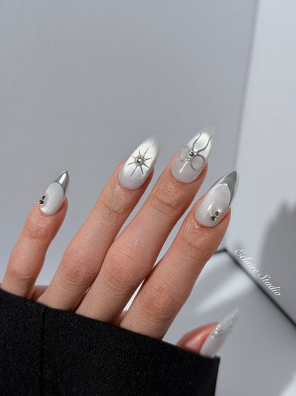 Silver cat-eye press-on nails featuring glazed chrome French tips and fine-line bow and starburst designs.