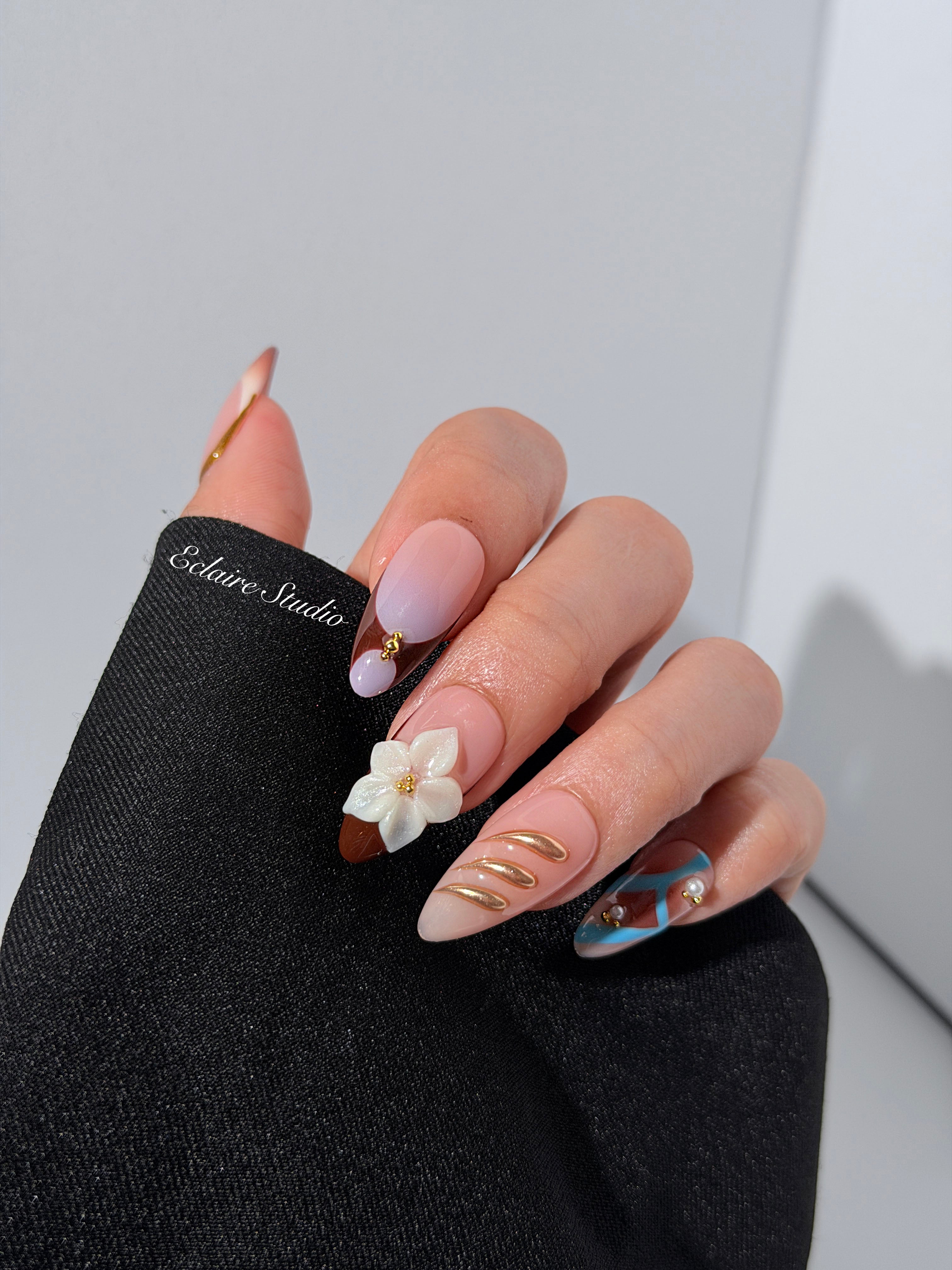 Warm gradient nails with gold trim, 3D white flowers, and blue accents inspired by the Nutcracker character
