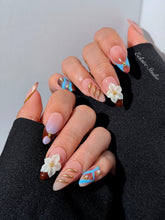 Warm gradient nails with gold trim, 3D white flowers, and blue accents inspired by the Nutcracker character
