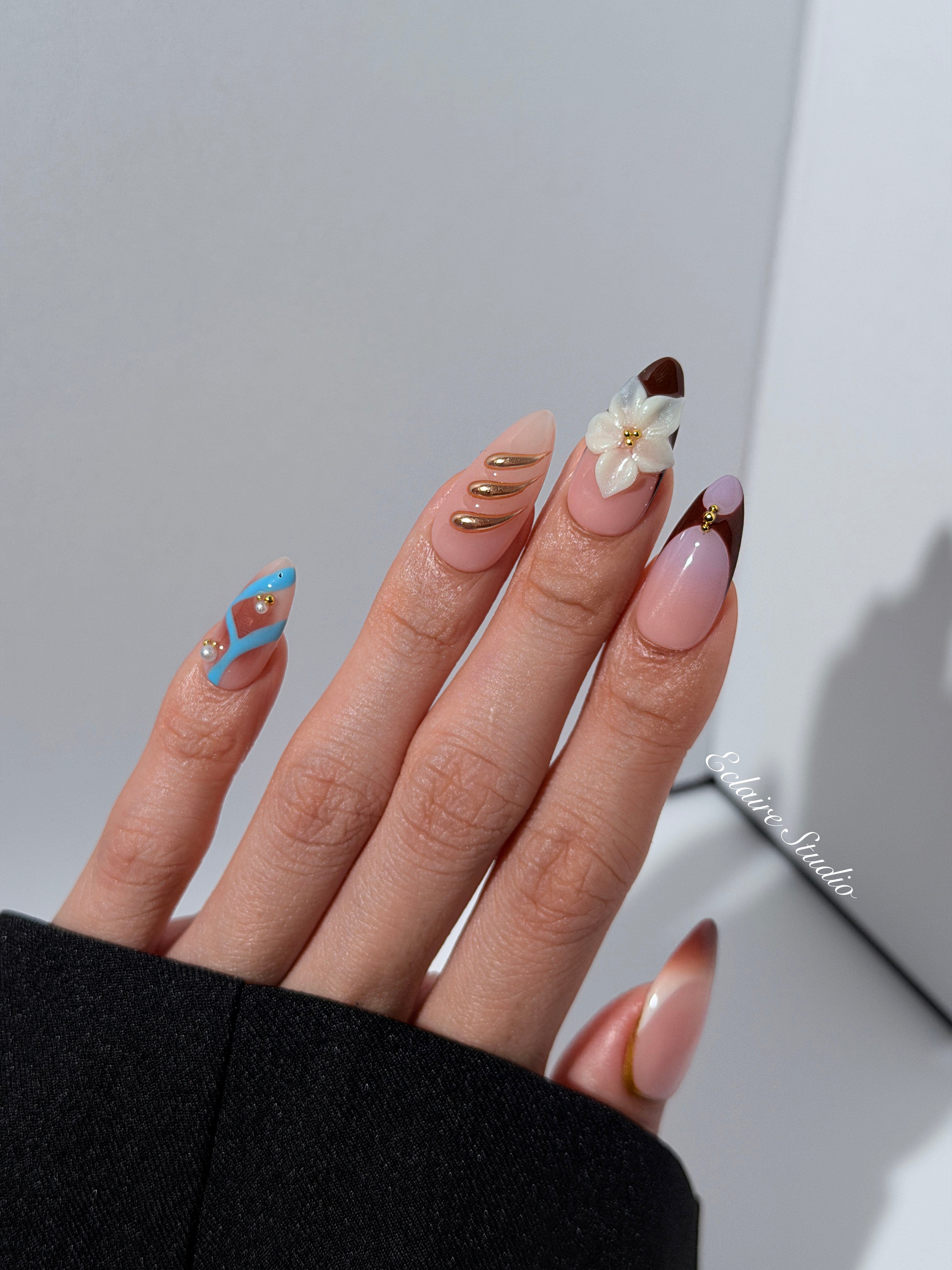 Warm gradient nails with gold trim, 3D white flowers, and blue accents inspired by the Nutcracker character