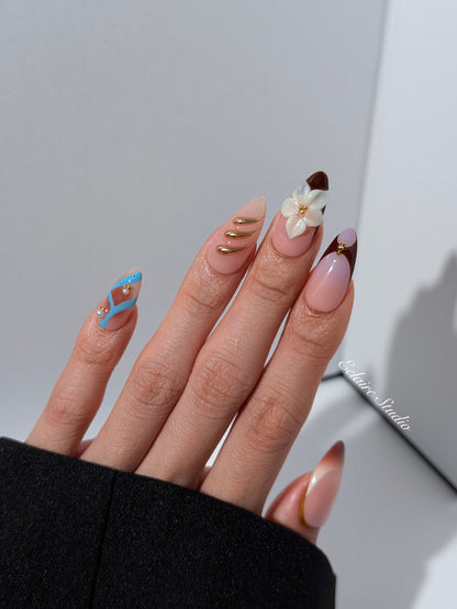 Warm gradient nails with gold trim, 3D white flowers, and blue accents inspired by the Nutcracker character