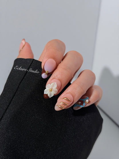 Warm gradient nails with gold trim, 3D white flowers, and blue accents inspired by the Nutcracker character