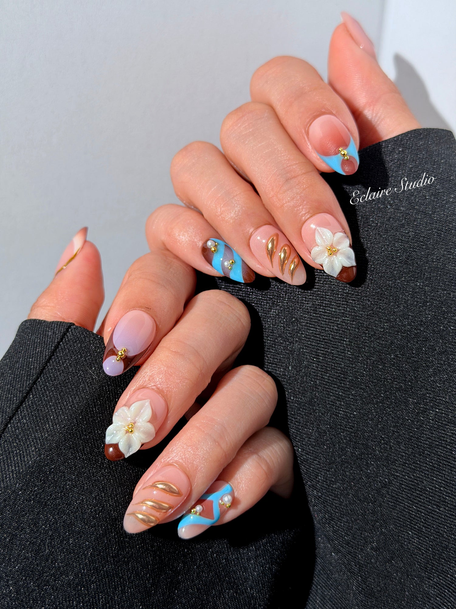 Warm gradient nails with gold trim, 3D white flowers, and blue accents inspired by the Nutcracker character