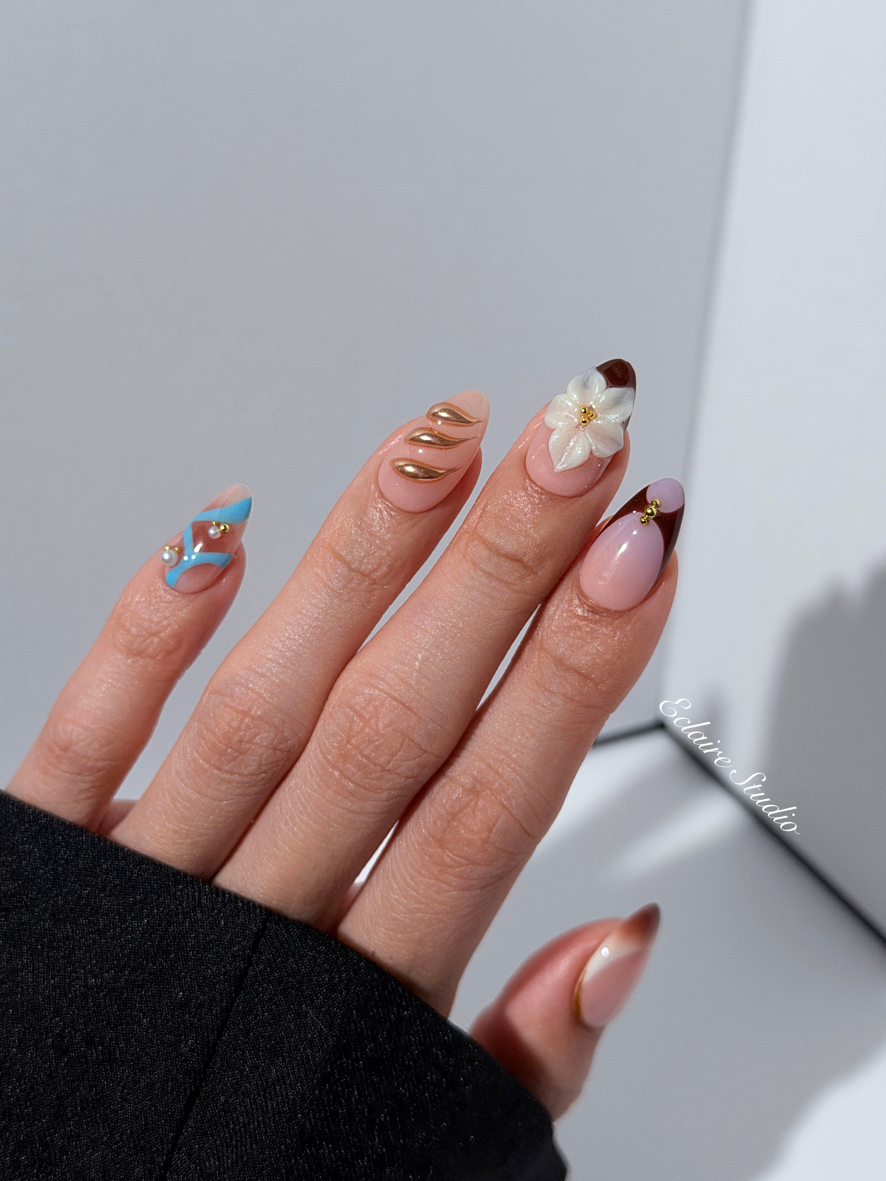 Warm gradient nails with gold trim, 3D white flowers, and blue accents inspired by the Nutcracker character