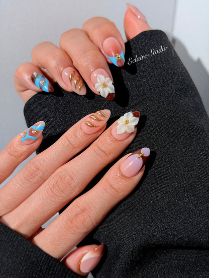 Warm gradient nails with gold trim, 3D white flowers, and blue accents inspired by the Nutcracker character