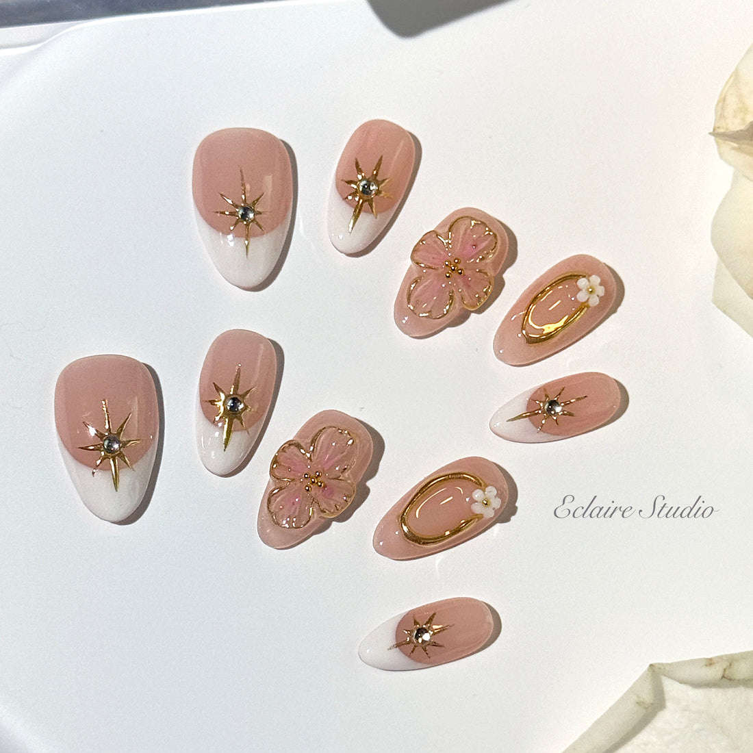 🤍 Classic nude-pink base with crisp white French tips

🌸 3D molded cherry blossom florals for a soft, feminine finish

✨ Gold starburst gems and oval contours for a hint of luxury

💫 Handcrafted artistry for an elevated, reusable experience

