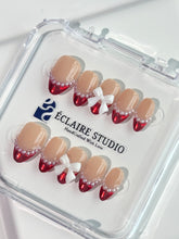 Red Ribbon press-on nails with glazed red chrome French tips, pearl trim, and 3D white bow accents.”
