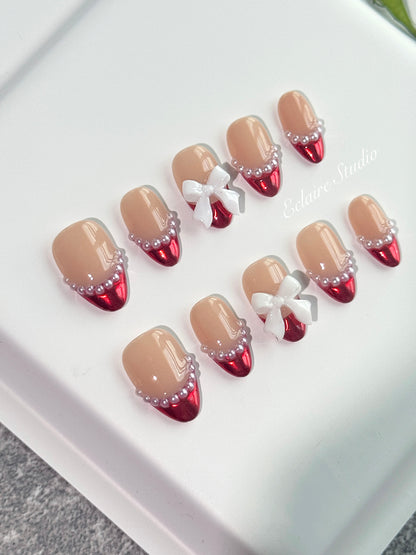Red Ribbon press-on nails with glazed red chrome French tips, pearl trim, and 3D white bow accents.”