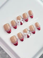 Red Ribbon press-on nails with glazed red chrome French tips, pearl trim, and 3D white bow accents.”