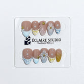 Artisanal resort-style press-on nails with a sheer nude base, pastel blue and yellow striped French tips, 3D sculpted flowers, and gold starfish charms with mini pearls.
