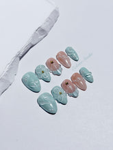 Eclaire Nail Studio 3D Summer short almond press-on nails featuring a light aqua glazed base and peachy-nude accent nails with 3D sculpted ocean waves, 3D flowers, and seashell tips with mini pearls and gold stars.